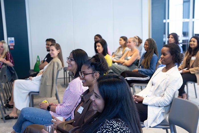 A diverse group of women sit as part of an audience.