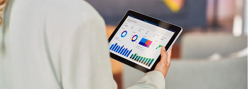 A hand holding a tablet that shows statistics and graphs.