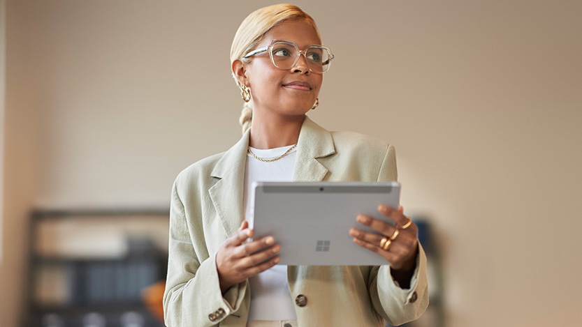 A woman holding a tablet looks away from the camera.