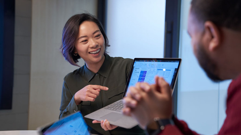 Two people smiling while interacting with laptop.