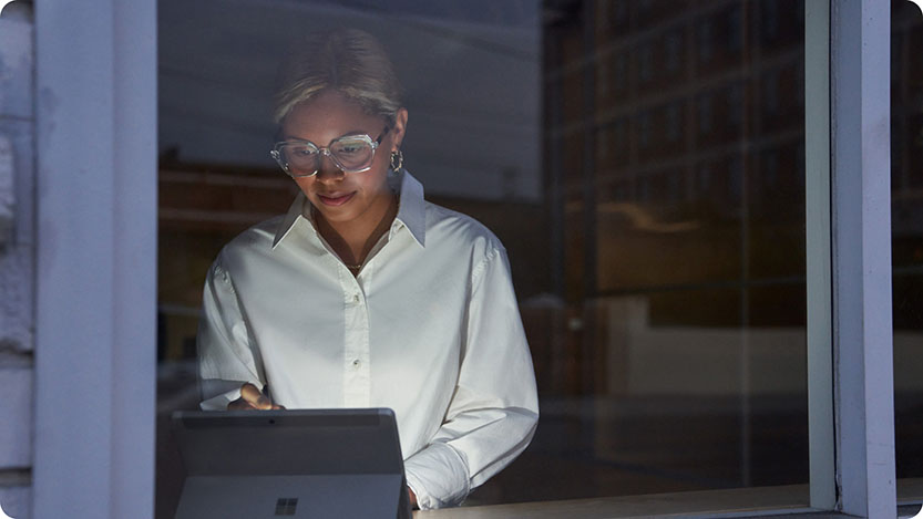 Person smiling while using a tablet near a window at home.