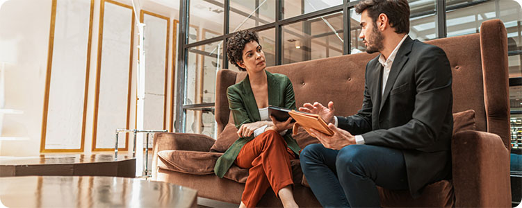 Two coworkers talking while holding a tablet in an office setting